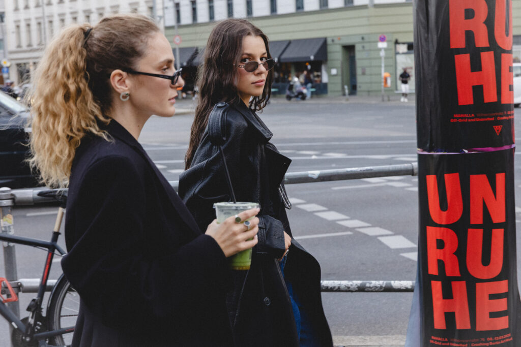 Dwie modelki w czarnych stylizacjach podczas miejskiej sesji zdjęciowej PARTS JEWELRY w Berlinie, prezentujące autorską biżuterię.
