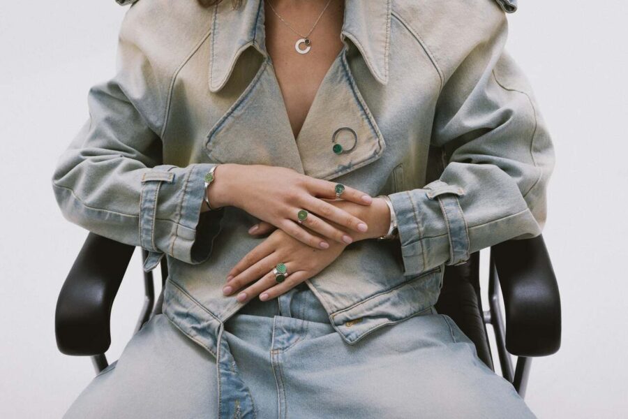 Modelka w jeansowej stylizacji nosząca srebrną biżuterię z zielonym próbnikiem lakieru