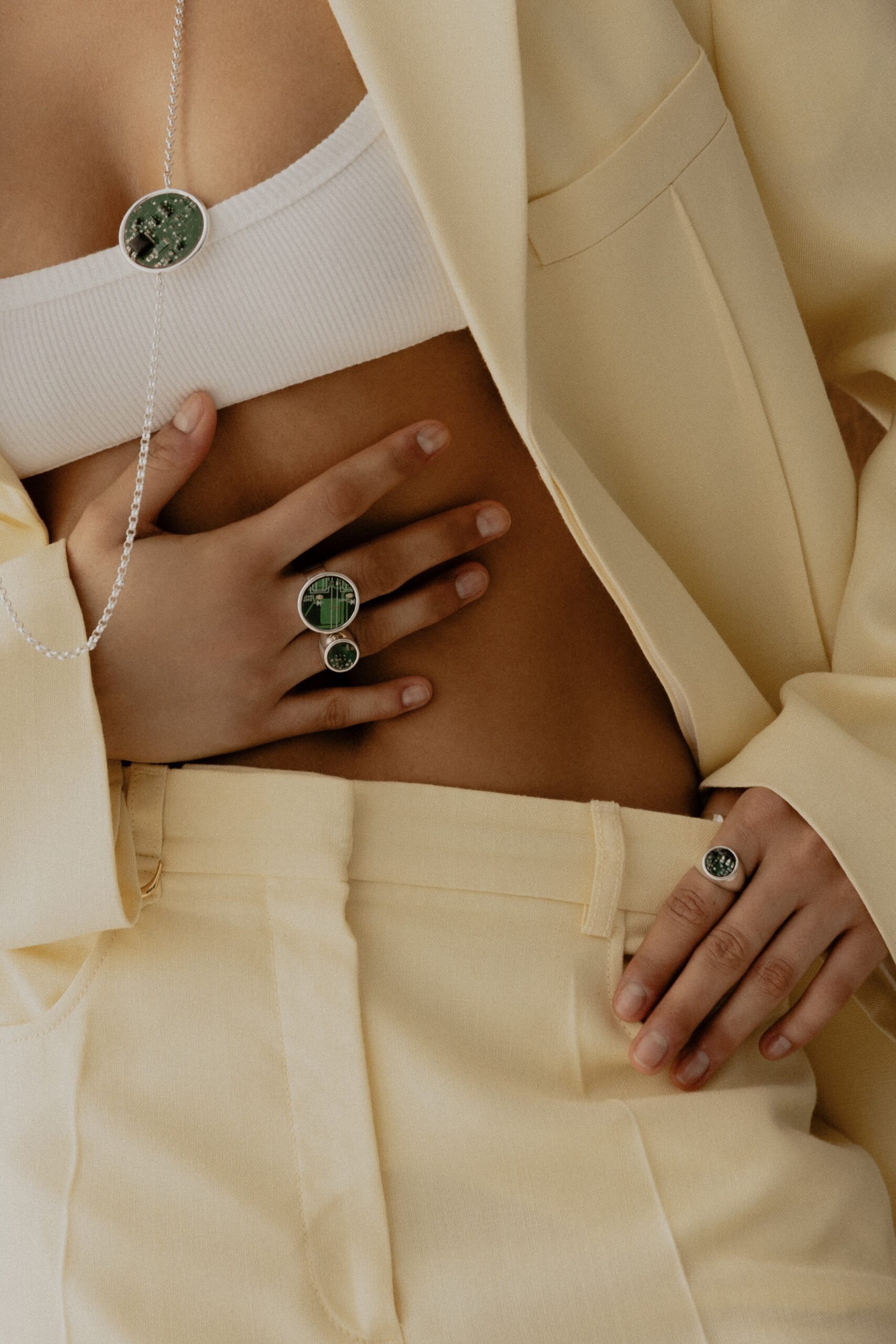 Modelka w jasnym garniturze nosząca biżuterię Ultra Parts Jewelry z układów scalonych Volvo – pierścionki i naszyjnik